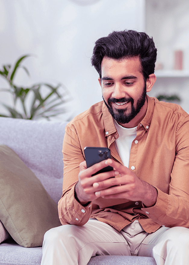 Man smiling at phone on couch
