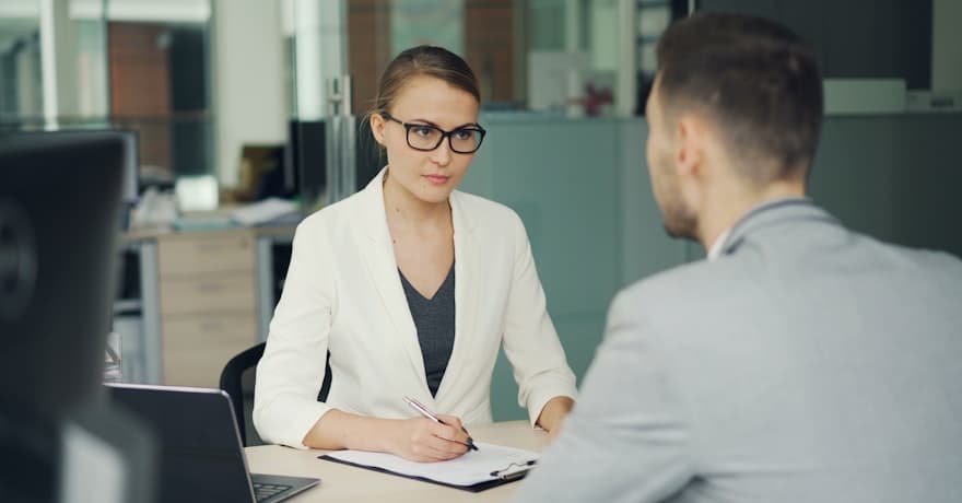 An interviewer taking notes opposite a candidate