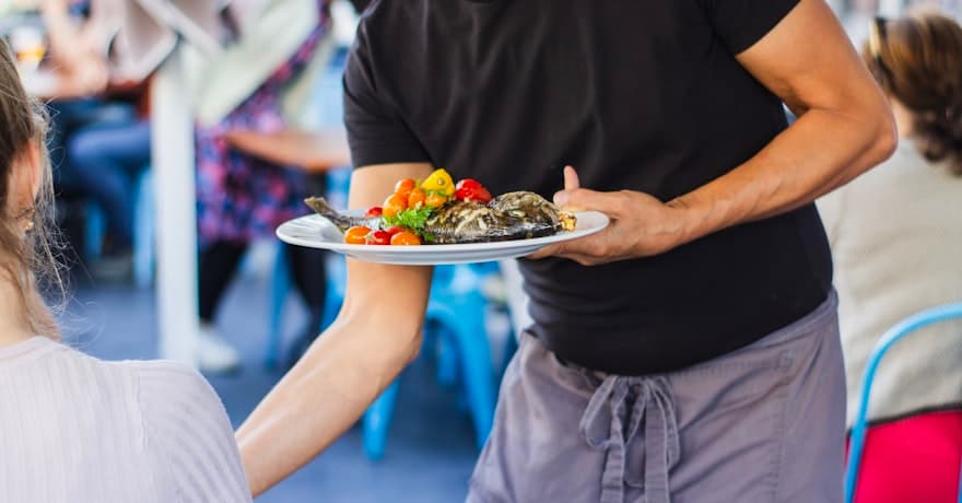 A server bringing a plated dish to a table