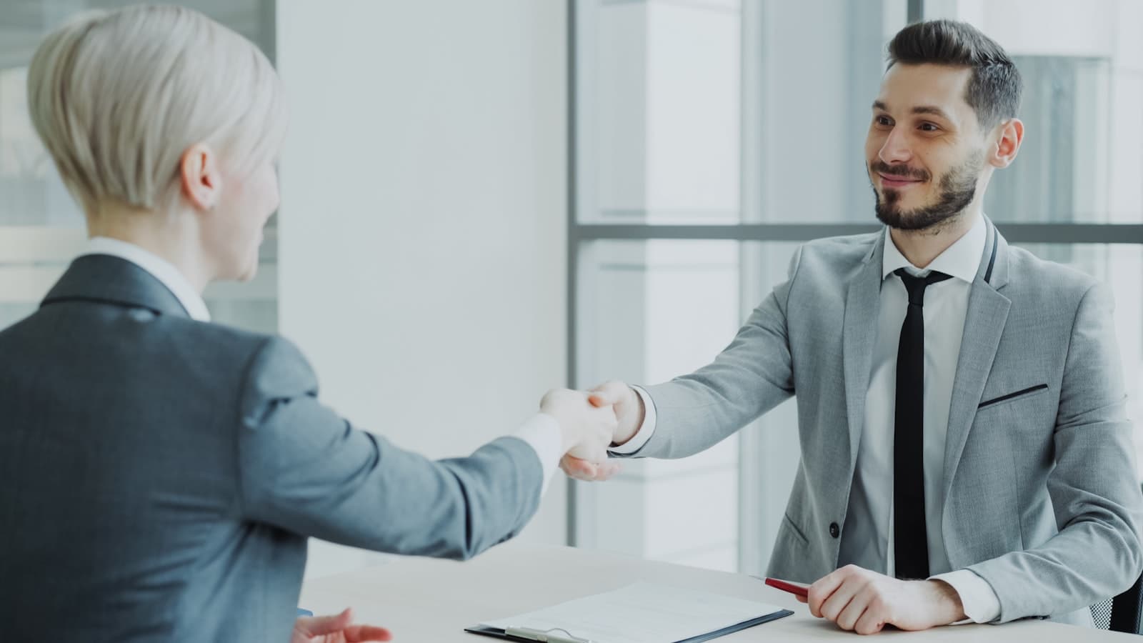 Two partners shaking hands over a signed agreement